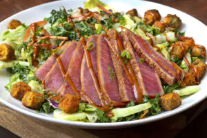Yellowfin tuna seared rare and served over a bed of kale and chopped romaine. Lightly tossed in a sesame lime dressing with shaved peppers, carrots, scallion, cabbage, and cilantro. Finished with fried okra and a southern peanut drizzle.