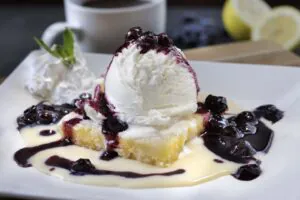 Decadent lemon curd and shortbread bar topped with vanilla ice cream, white chocolate bourbon sauce, blueberry compote, and whipped cream.